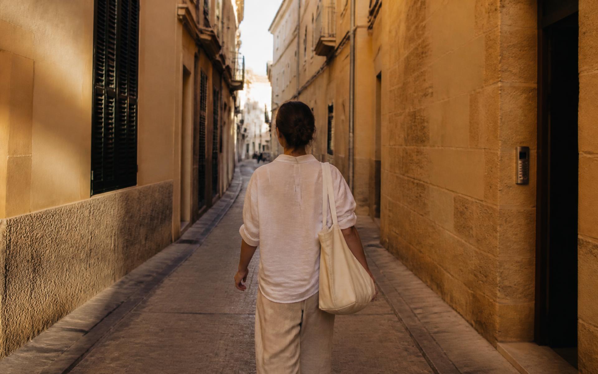 Early morning light in a narrow Palma old-town street as a woman walks through it